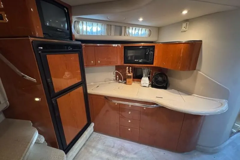 Slide: The Image of 2001 Sea Ray 380 Sundancer kitchen with wood cabinets, microwave, and fridge. - 29