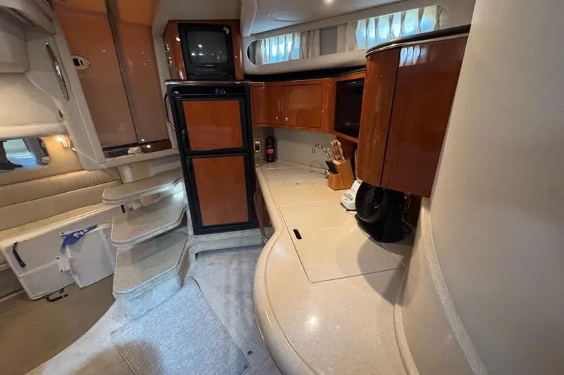 Slide: The Image of Interior of 2001 Sea Ray 380 Sundancer yacht, featuring a compact kitchen and seating area. - 30