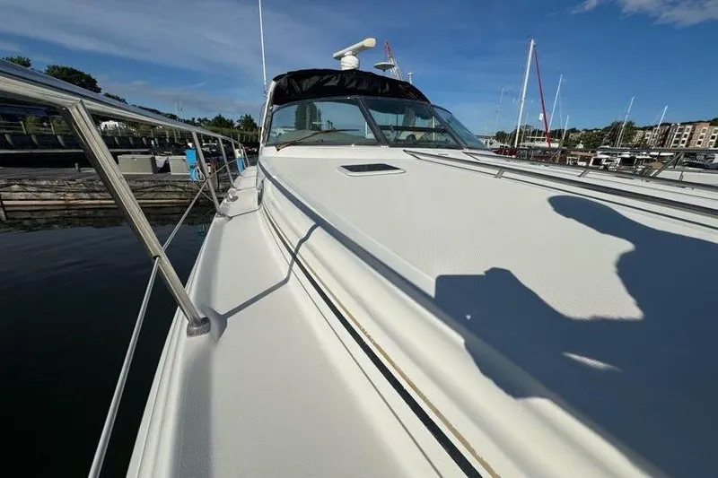 Slide: The Image of 2001 Sea Ray 380 Sundancer yacht docked, showcasing sleek deck design under clear blue sky. - 52