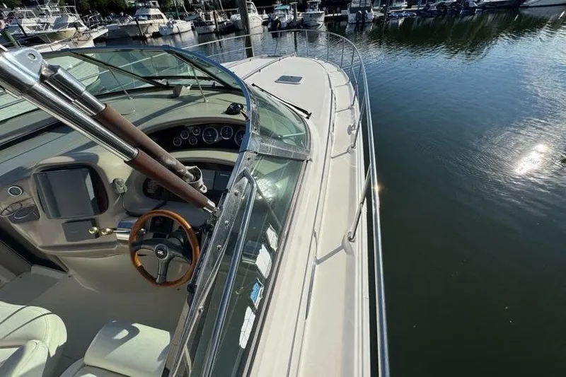 Slide: The Image of 2001 Sea Ray 380 Sundancer yacht docked, showcasing helm and deck, with marina view. - 55