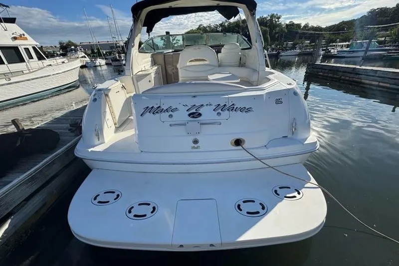Slide: The Image of 2001 Sea Ray 380 Sundancer docked at marina, rear view with "Make 'N' Waves" text. - 56