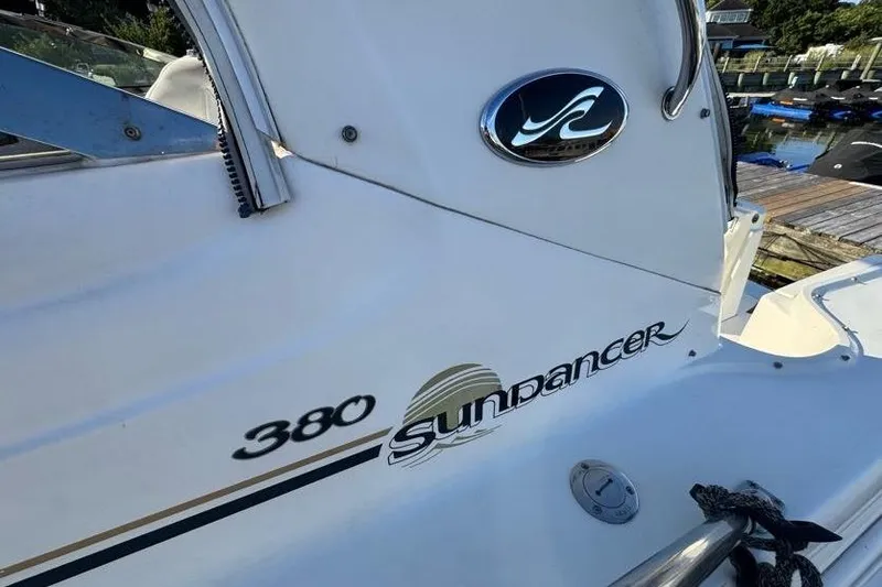 Slide: The Image of 2001 Sea Ray 380 Sundancer boat docked, showcasing sleek design and logo. - 57