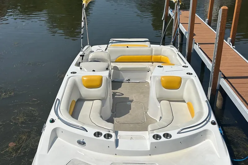 Slide: The Image of 2014 Hurricane SunDeck Sport 188 IO boat docked, featuring yellow and white seating. - 2