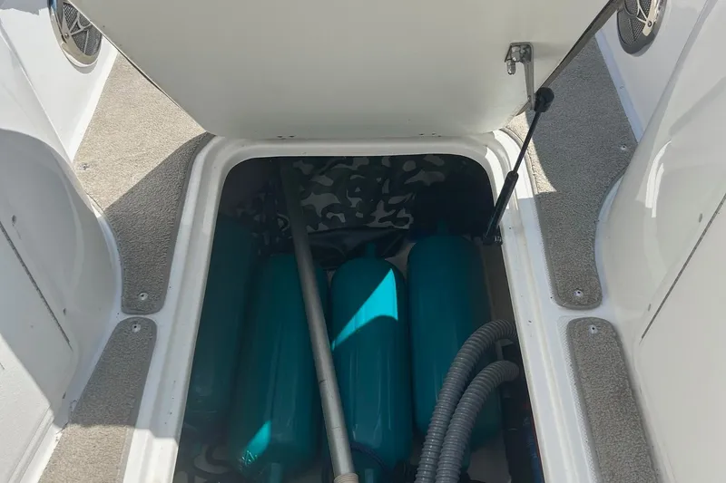 Slide: The Image of Open storage compartment on 2014 Hurricane SunDeck Sport 188 IO boat, showing blue fenders and hoses. - 8