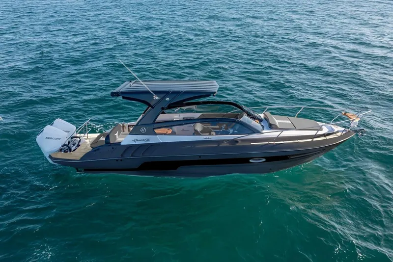 Slide: The Image of 2025 Hanover 305 Gray & Black Edition boat cruising on clear blue water. - 2