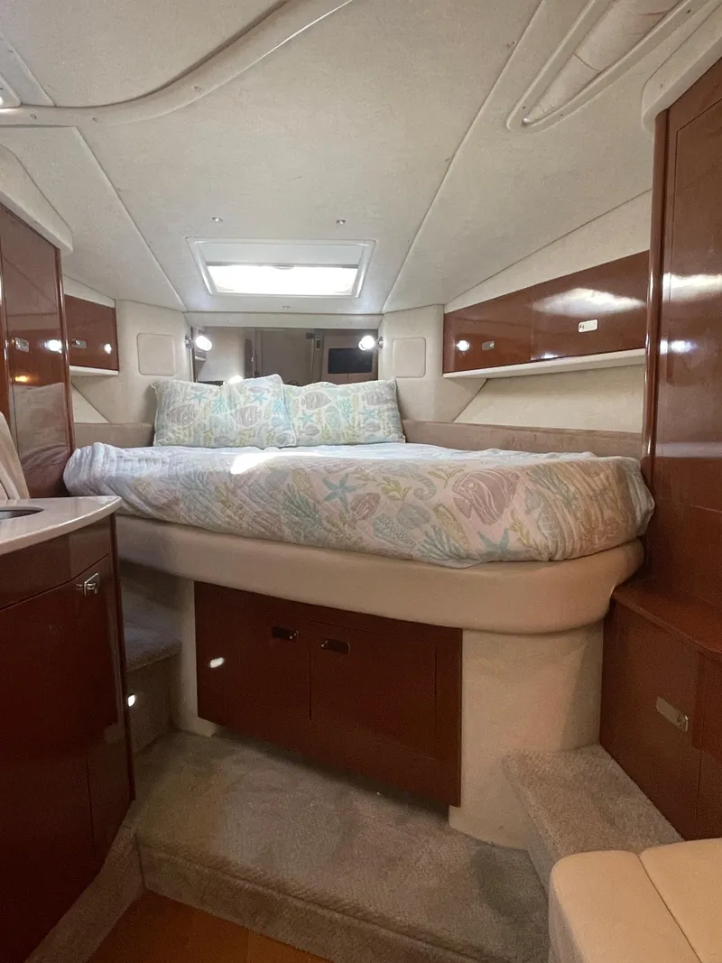 Slide: The Image of 2012 Sea Ray 330 Sundancer cabin with bed, skylight, and wooden cabinetry. - 14