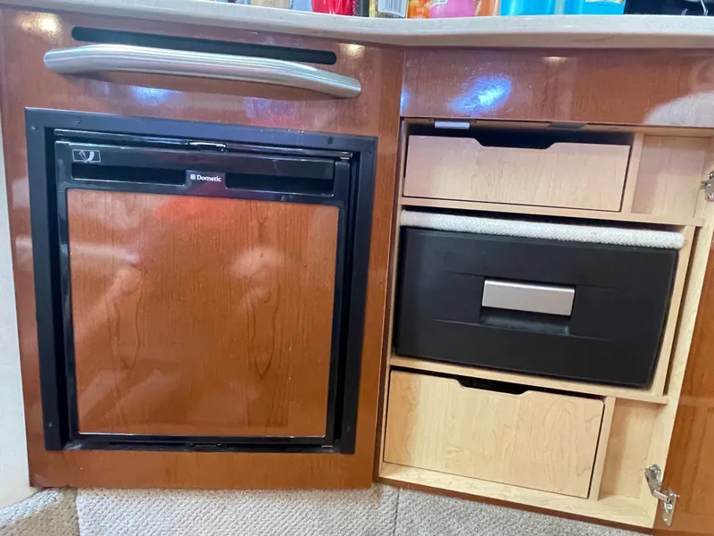 Slide: The Image of Interior of 2012 Sea Ray 330 Sundancer with compact fridge and storage drawers. - 19