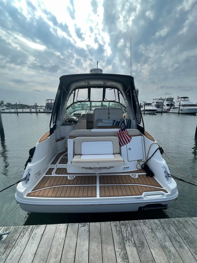 Slide: The Image of 2012 Sea Ray 330 Sundancer docked, showcasing sleek design and spacious deck under a cloudy sky. - 8