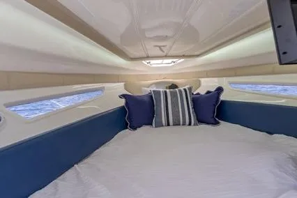 Slide: The Image of 2024 Hanover 305 White & Blue Edition boat interior with cozy bed and nautical decor. - 10