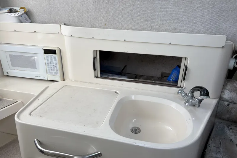 Slide: The Image of 1994 Grady-White Marlin 280 boat interior with sink, microwave, and storage area. - 6
