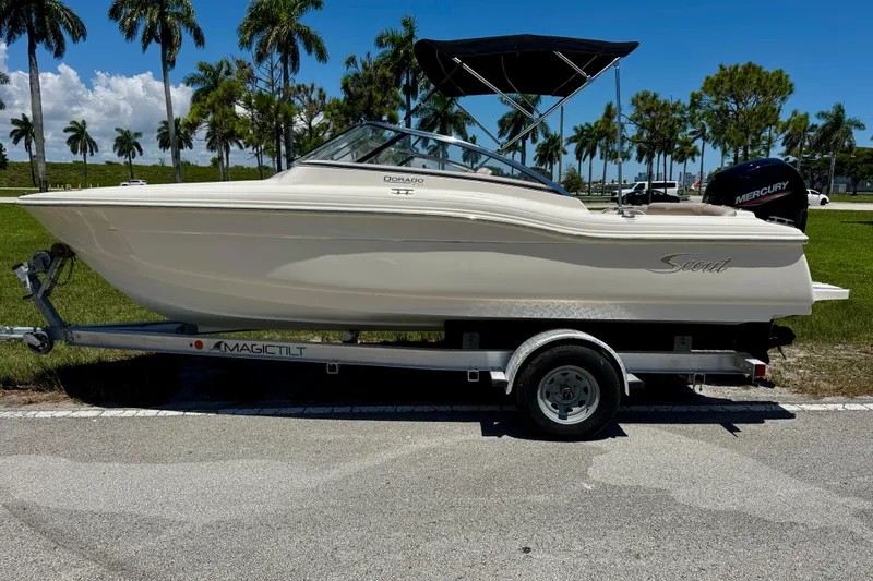 The Image of 2021 Scout 210 Dorado boat on trailer, parked near palm trees under clear blue sky. - 0