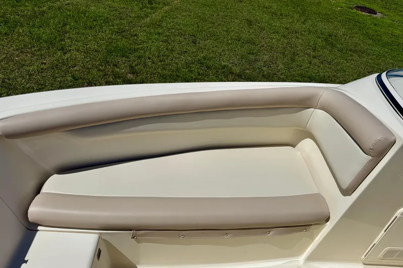Slide: The Image of 2021 Scout 210 Dorado boat interior seating with beige upholstery, set against a grassy background. - 11
