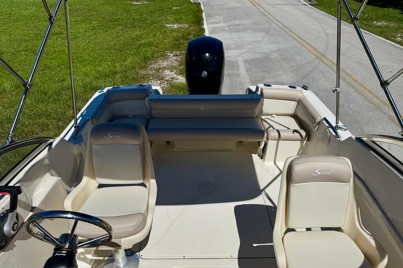 Slide: The Image of 2021 Scout 210 Dorado boat interior with seating and steering wheel, parked on a road. - 13