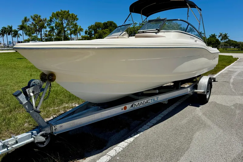Slide: The Image of 2021 Scout 210 Dorado boat on trailer, parked outdoors under clear blue sky. - 2