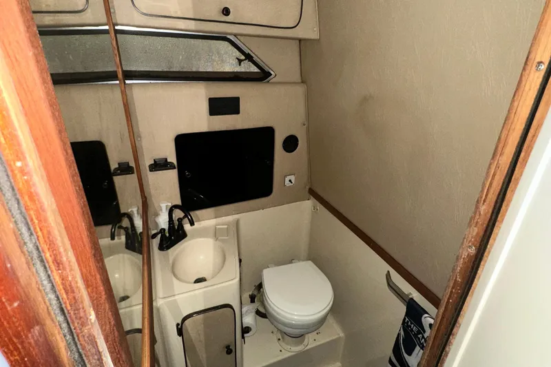 Slide: The Image of 1986 Sea Ray 340 Express Cruiser bathroom with sink, toilet, and mirror. - 23