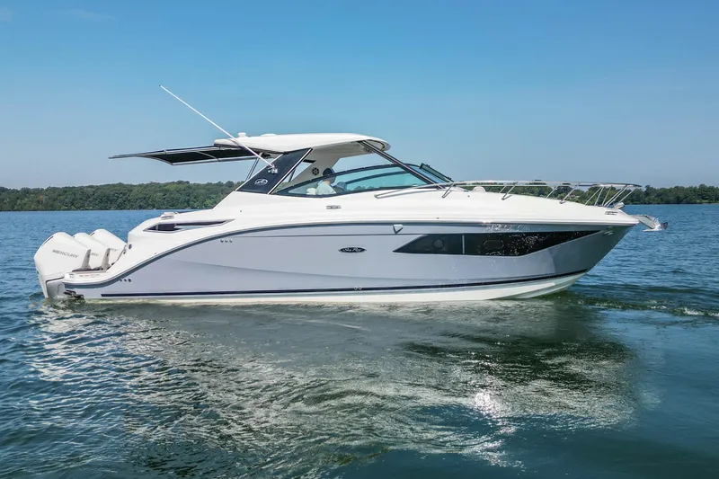 The Image of 2022 Sea Ray Sundancer 320 Outboard cruising on a serene lake under clear blue skies. - 1