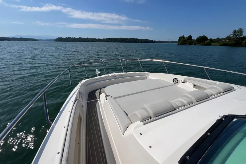 Slide: The Image of 2022 Sea Ray Sundancer 320 Outboard cruising on a serene lake under a clear blue sky. - 23