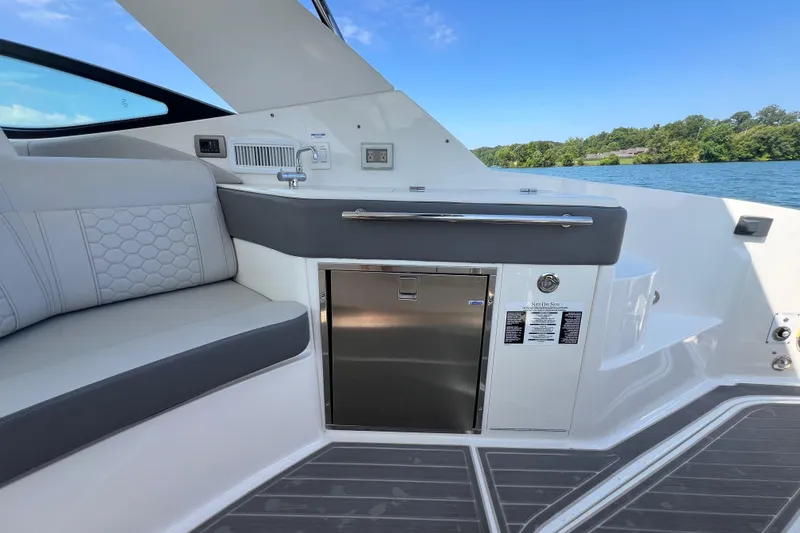 Slide: The Image of 2022 Sea Ray Sundancer 320 Outboard interior with seating, sink, and storage, on a sunny day. - 27
