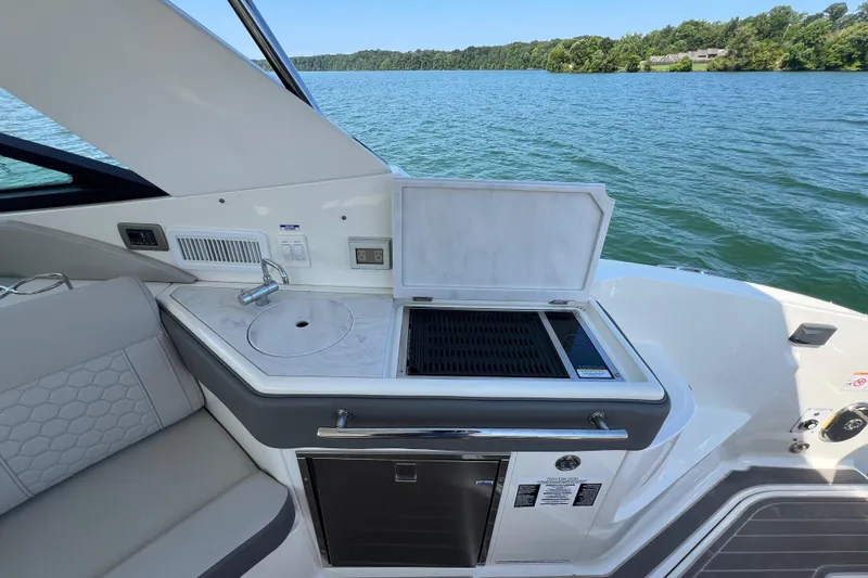Slide: The Image of 2022 Sea Ray Sundancer 320 Outboard boat kitchen with grill and sink by the water. - 28