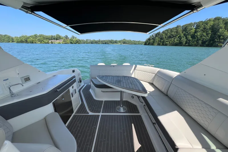 Slide: The Image of 2022 Sea Ray Sundancer 320 Outboard interior with seating and table on a lake. - 31