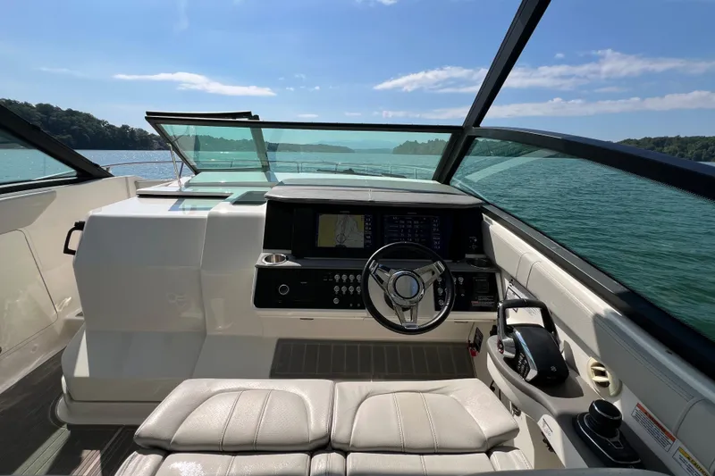 Slide: The Image of 2022 Sea Ray Sundancer 320 Outboard helm with modern controls, cruising on a sunny lake. - 34