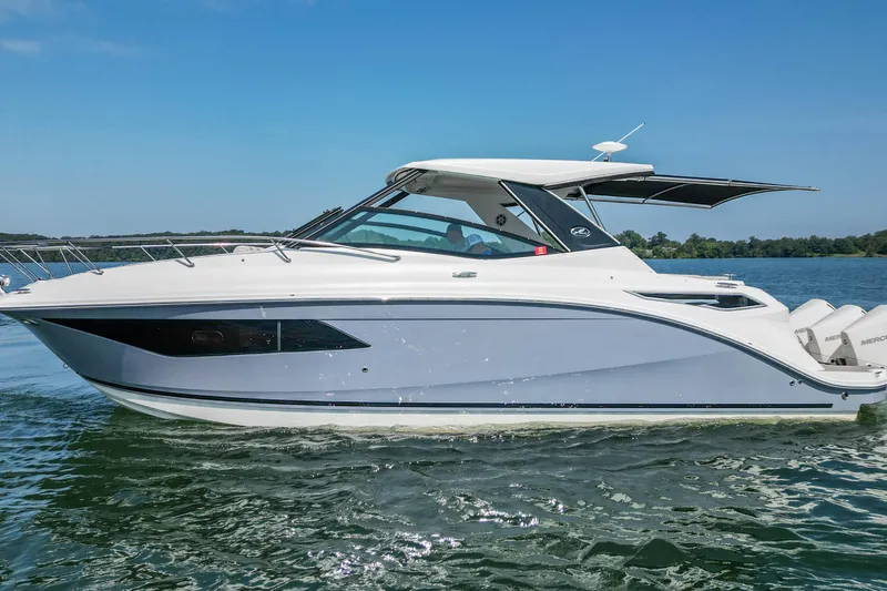 Slide: The Image of 2022 Sea Ray Sundancer 320 Outboard cruising on a serene lake under a clear blue sky. - 5