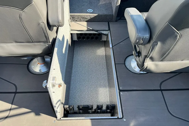 Slide: The Image of 2026 Lund 2275 Baron boat interior with open storage compartment between seats. - 16