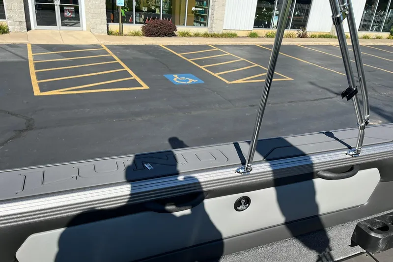 Slide: The Image of 2026 Lund 2275 Baron boat detail with chrome railings and parking lot background. - 31