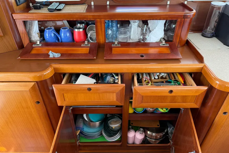 Slide: The Image of Wooden kitchen storage on 2007 Beneteau Swift Trawler 42, featuring drawers and cabinets with utensils and dishes. - 44