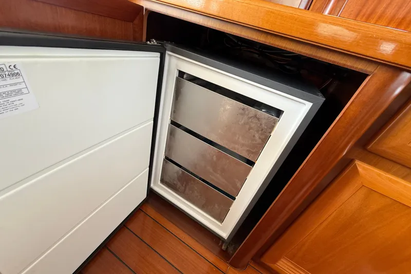 Slide: The Image of Open refrigerator in 2007 Beneteau Swift Trawler 42, showcasing wooden interior cabinetry. - 47