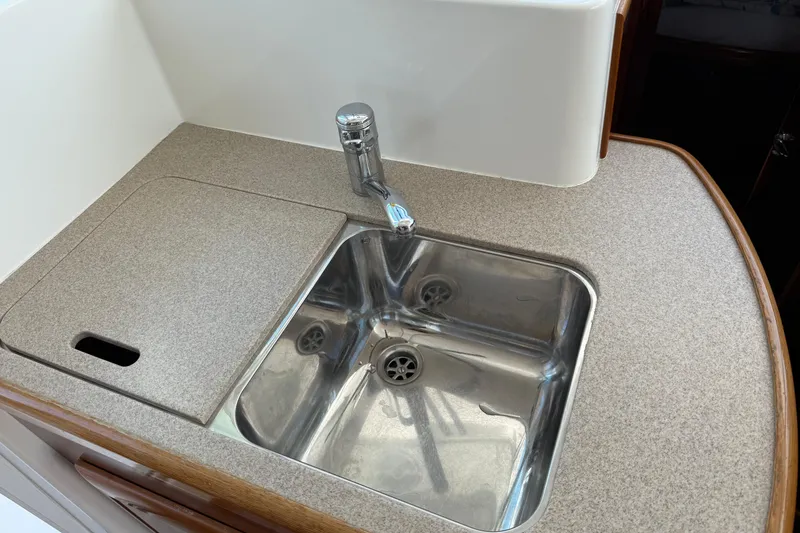 Slide: The Image of Kitchen sink area in 2007 Beneteau Swift Trawler 42, featuring stainless steel sink and faucet. - 52