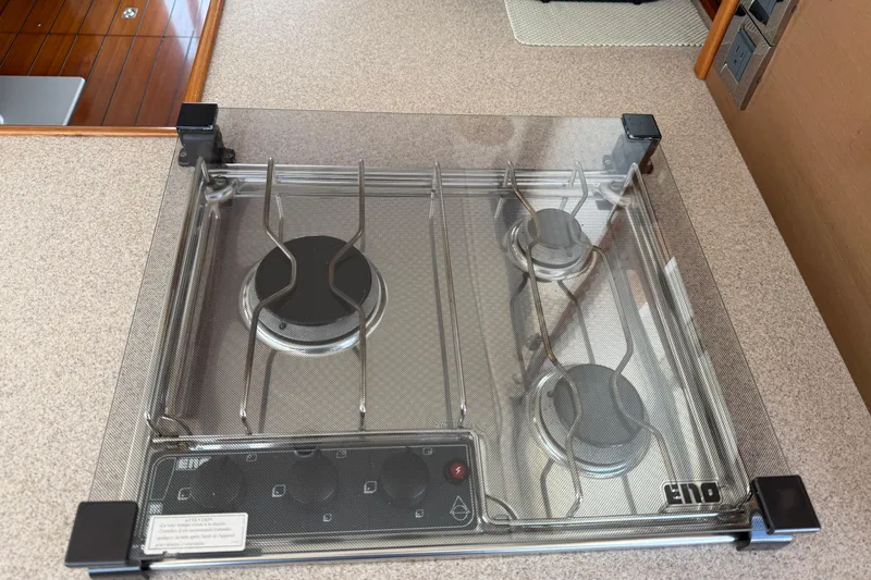 Slide: The Image of Gas stove on 2007 Beneteau Swift Trawler 42 yacht, featuring three burners and protective cover. - 54