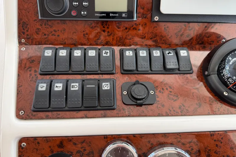 Slide: The Image of Control panel of a 2007 Beneteau Swift Trawler 42 with various switches and a compass. - 82