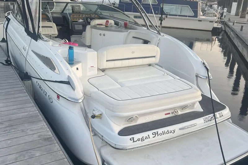 Slide: The Image of 2008 Cobalt 323 boat docked, featuring white seating and dashboard, named "Legal Holiday." - 2