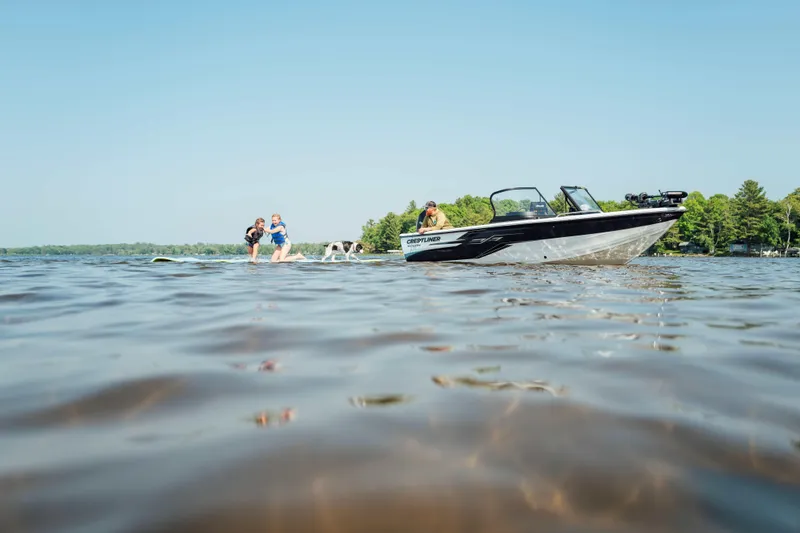 Slide: The Image of 2026 Crestliner 1950 Sportfish boat on a lake with people and a dog nearby. - 16