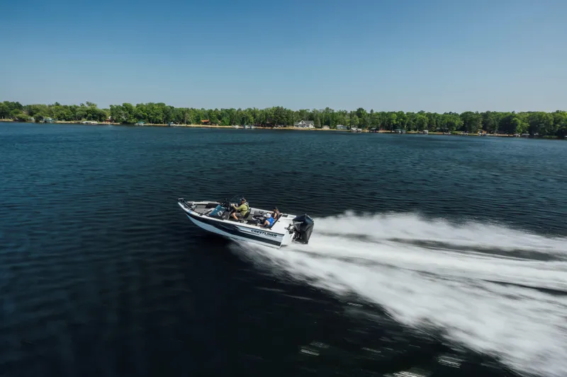 Slide: The Image of 2026 Crestliner 1950 Sportfish speeding on a serene lake under a clear blue sky. - 17