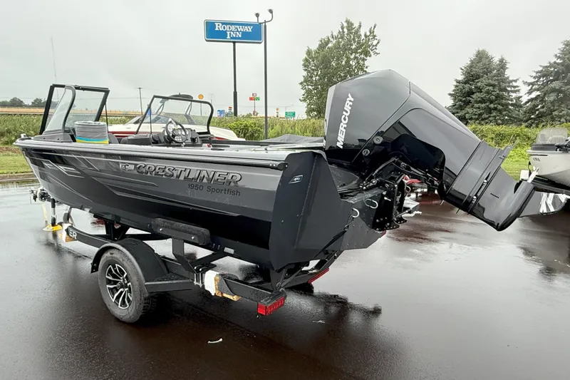 Slide: The Image of 2026 Crestliner 1950 Sportfish boat on trailer, parked near Rodeway Inn sign. - 4