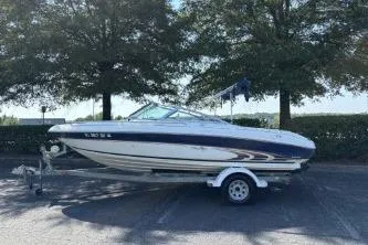 The Image of 1998 Sea Ray 190 Bow Rider boat on trailer, parked outdoors under trees. - 1