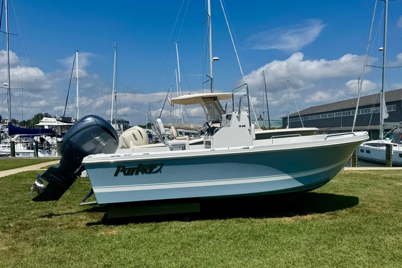The Image of 2026 Parker 18SE Center Console boat displayed on grass near marina. - 1