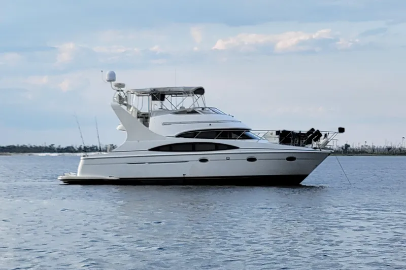 Slide: The Image of 2002 Carver 410 Sport Sedan yacht anchored on calm water under a cloudy sky. - 0