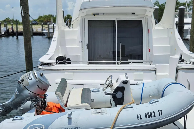 Slide: The Image of 2002 Carver 410 Sport Sedan with inflatable boat and Honda outboard motor at dock. - 2