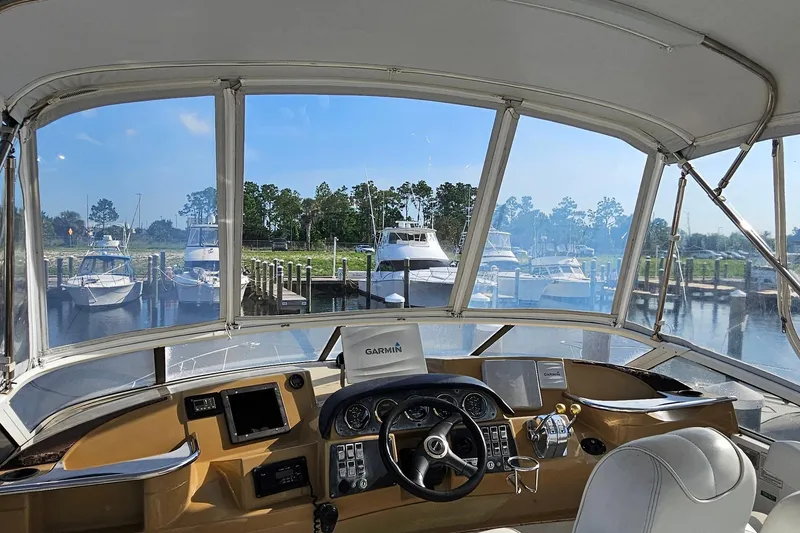 Slide: The Image of 2002 Carver 410 Sport Sedan helm view, marina backdrop, clear skies. - 5