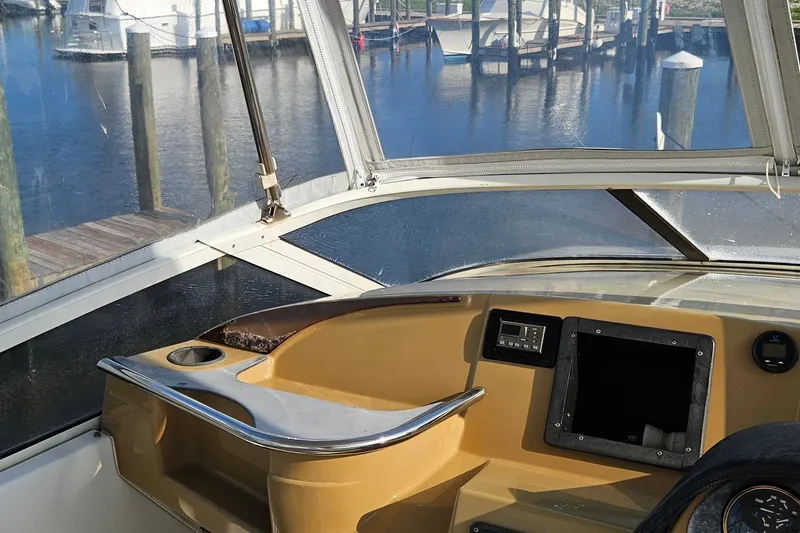 Slide: The Image of 2002 Carver 410 Sport Sedan helm with marina view, featuring control panel and cup holder. - 6