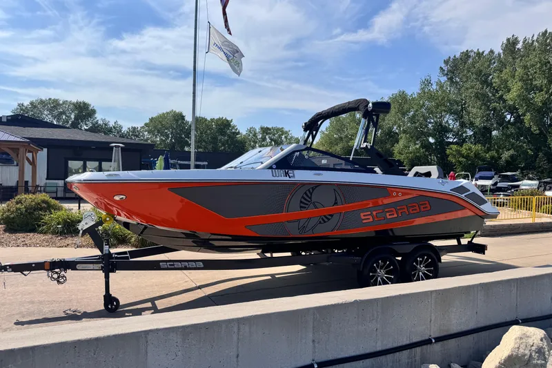 Slide: The Image of 2026 Scarab 235 LX Wake boat on trailer, vibrant orange and gray design. - 3