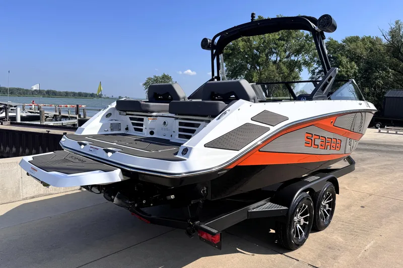 Slide: The Image of 2026 Scarab 235 LX Wake boat on trailer by the waterfront. - 5