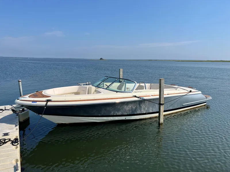 Slide: The Image of 2021 Chris-Craft Launch 27 boat docked on calm water under clear blue sky. - 5