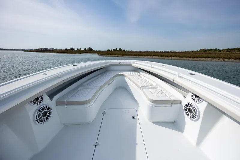 Slide: The Image of 2025 Yellowfin 34 Offshore boat interior with cushioned seating and speakers, on calm water. - 22
