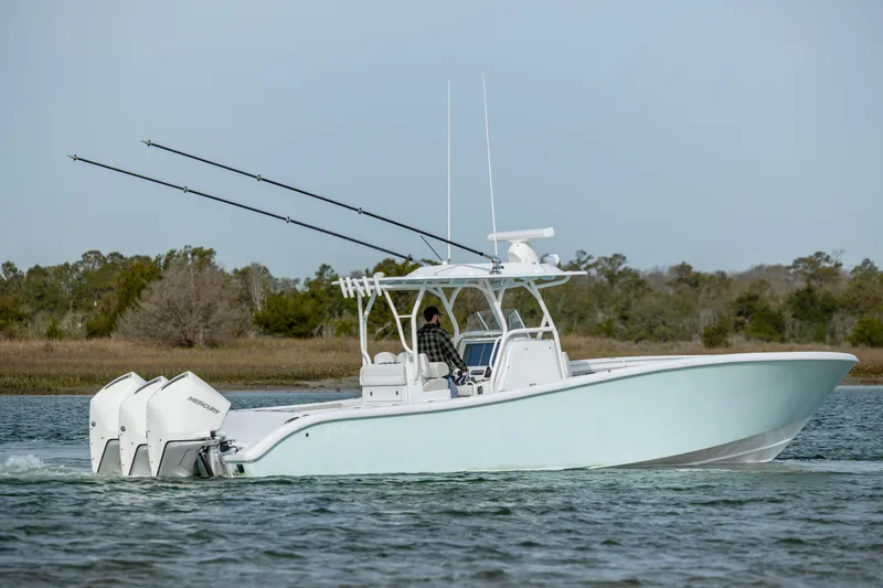 Slide: The Image of 2025 Yellowfin 34 Offshore boat cruising on a calm lake with trees in the background. - 5