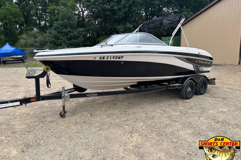 The Image of 2011 Tahoe Q7i boat on trailer, parked outdoors near trees and building. - 21