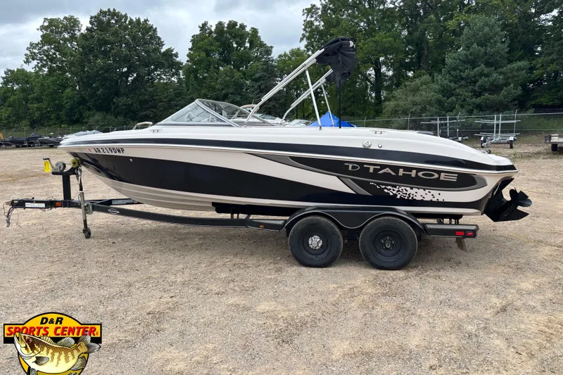 Slide: The Image of 2011 Tahoe Q7i boat on trailer, parked outdoors with trees in background. - 23